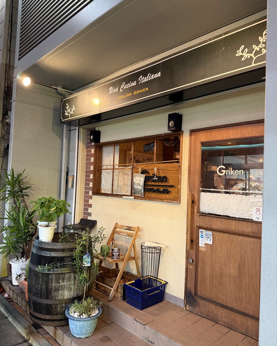 樽と植木が並ぶ、木の扉の入口